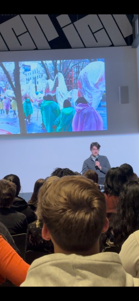 an audience looks on at the event as a photographer shares their work