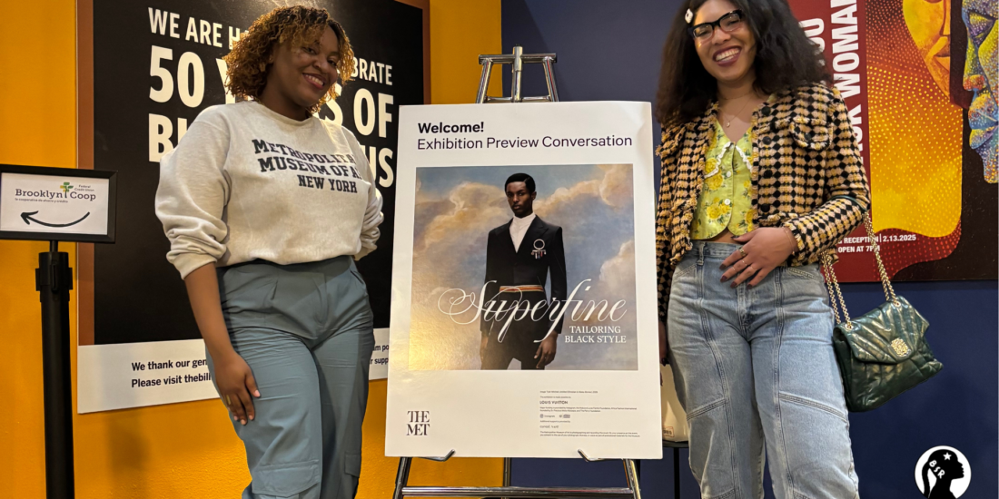 two women stand on either side of a poster advertising a new show at the Met