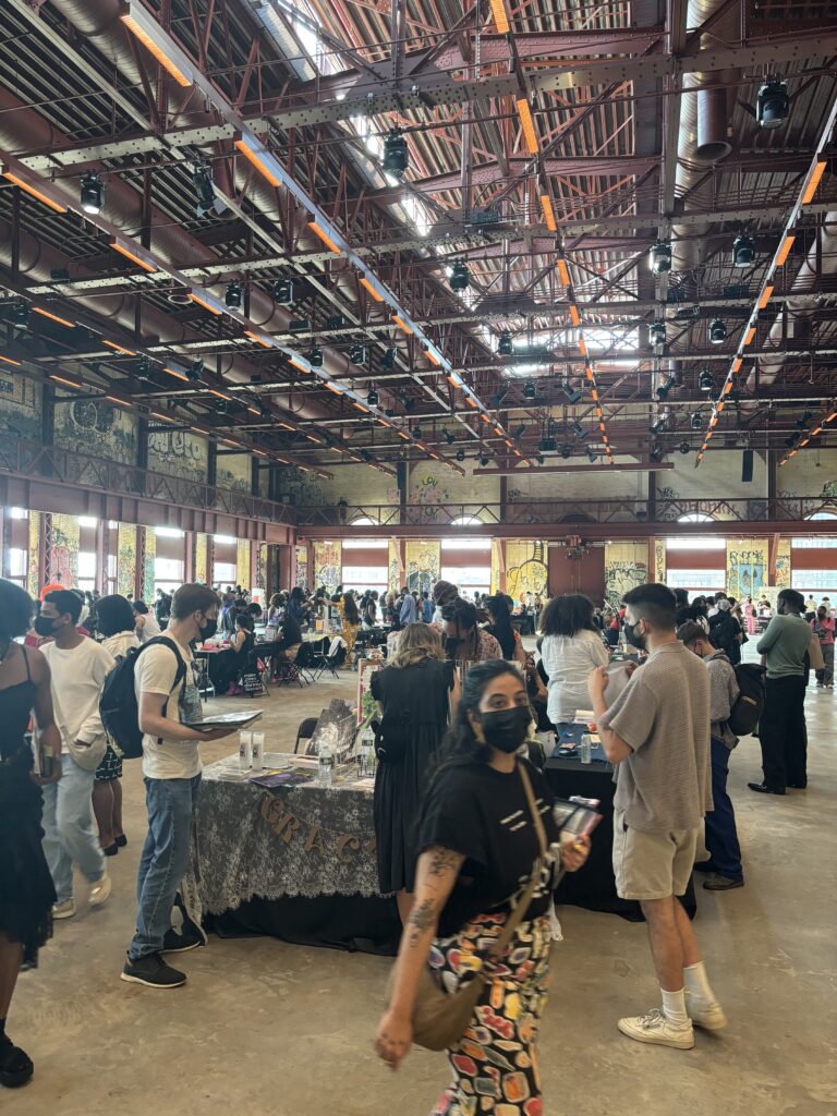 People gather around tables in a large industrial space.