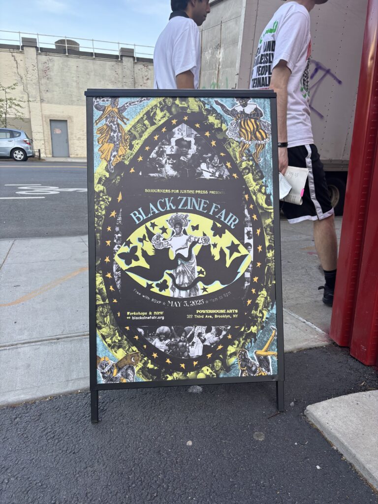 A standing sign floor sign holds the poster for the Black Zine Fair.