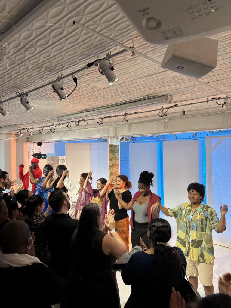 a row of actors holds hands and smiles at the audience
