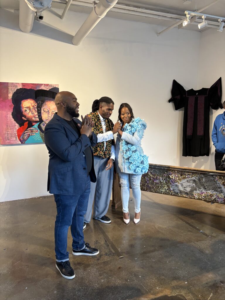 two man and a woman stand in an art gallery