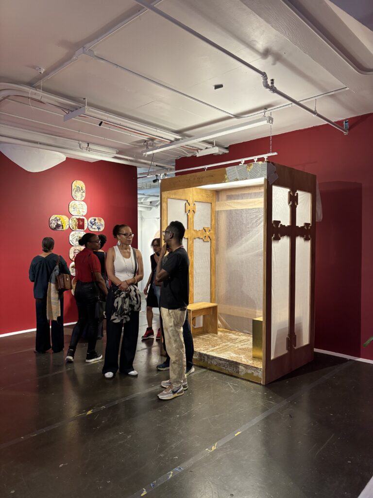 people stand in a gallery in front of a wooden booth