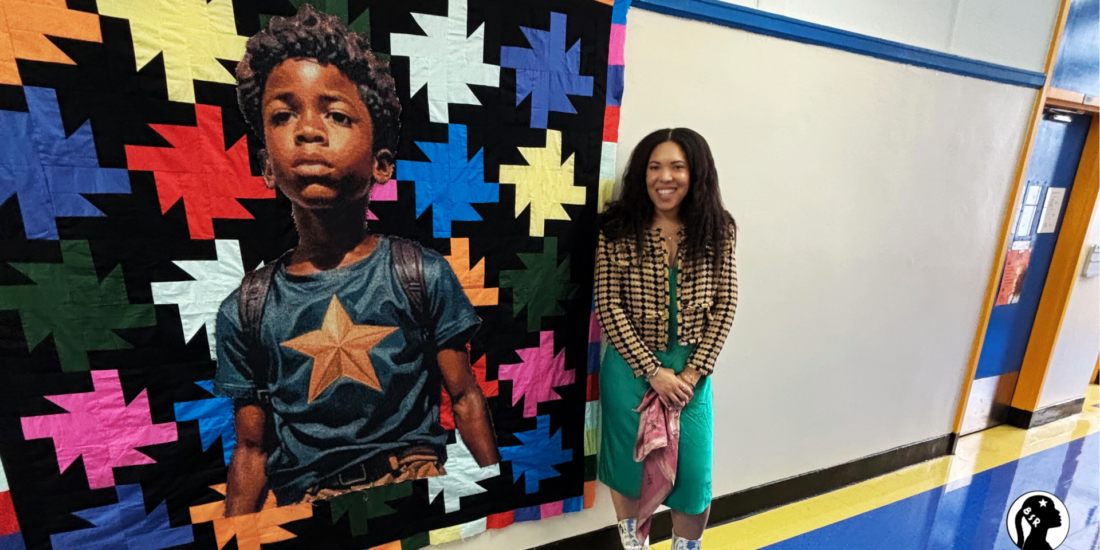Woman stands next to a colorful quilt that features a regal Black boy.