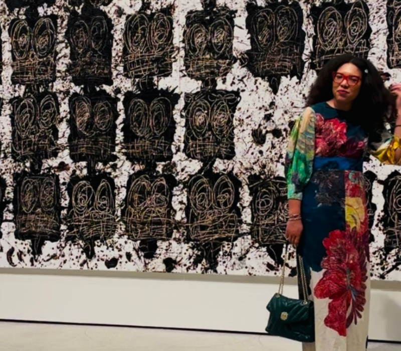 woman stands in front of artwork