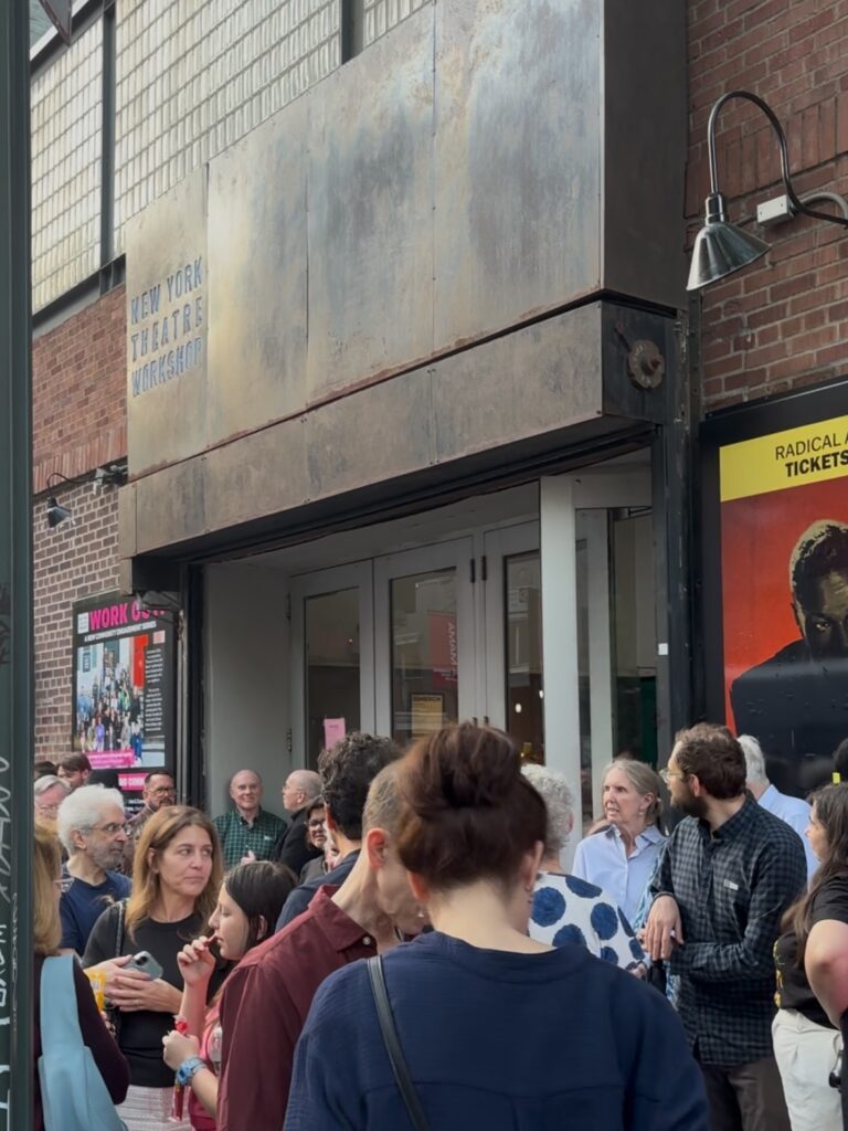 People stand outside of a theater entrance