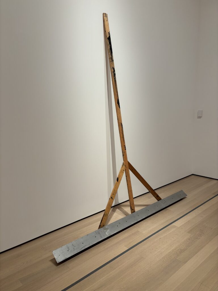 a rake like object leans up against a gallery wall