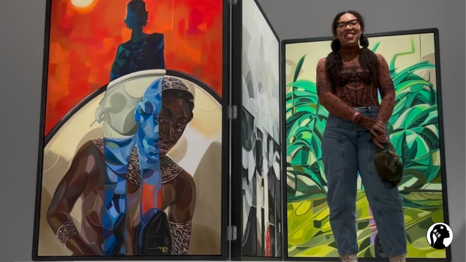 a woman stands in front of a large colorful artwork