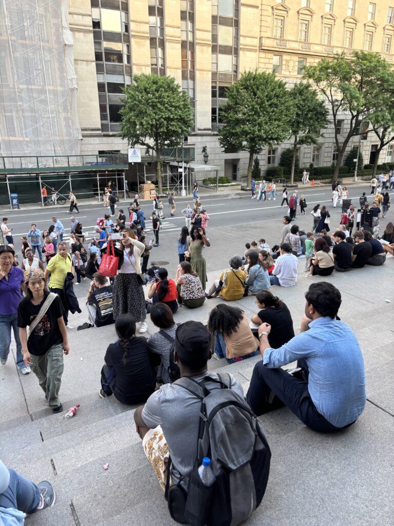 a lot of people sit on the steps of the Met