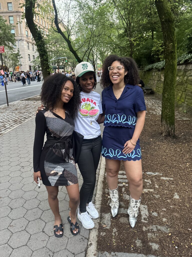 three women smile on the sidewalk