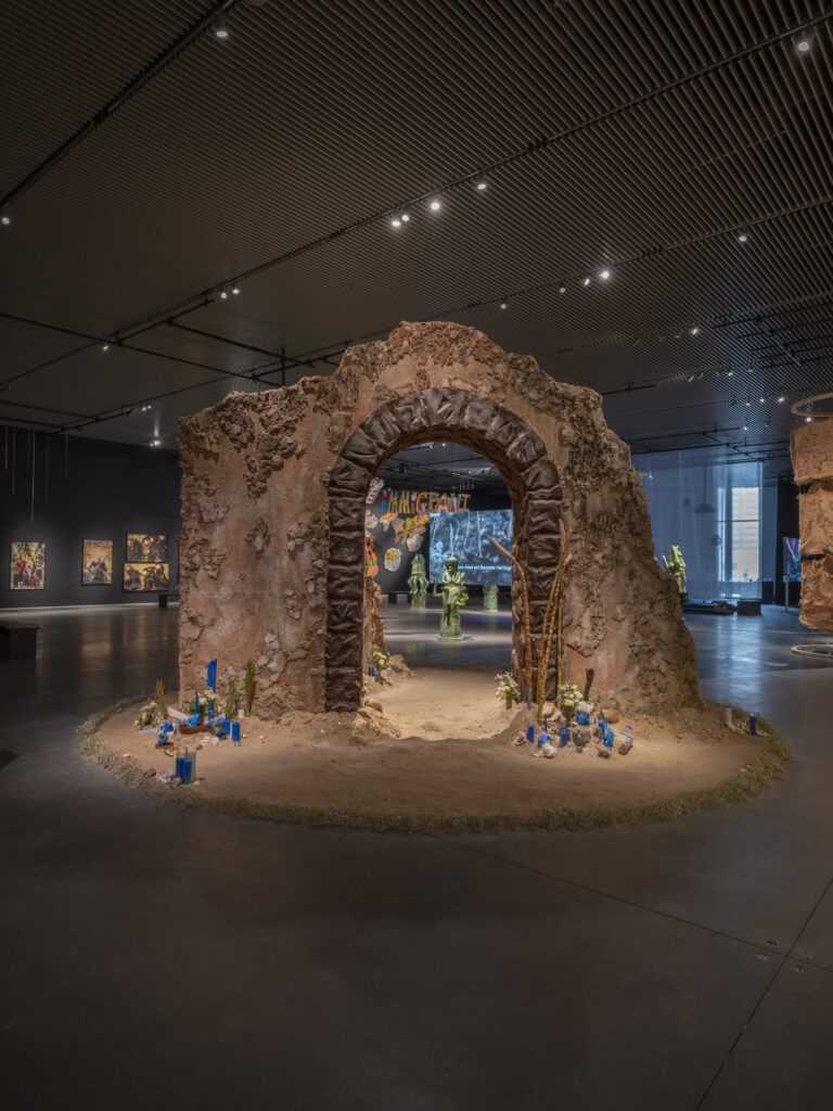 a stone archway stands in a circle of stand with blue candle near the base of the arch