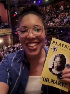 A woman smiles with a Playbill