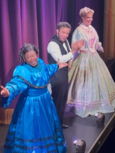 Three actors take a bow in front of a purple curtain