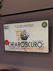 A poster for the play is projected on a screen