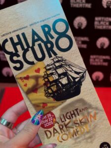 A hand holds out a playbill