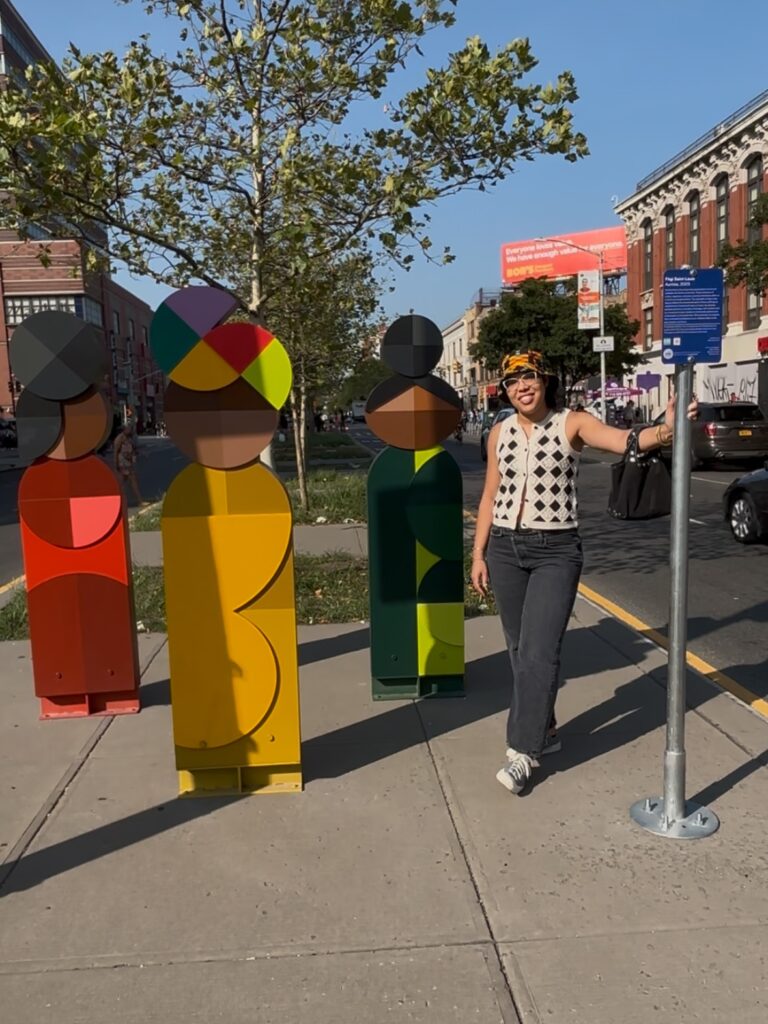 a woman stands next to a colorful sculpture