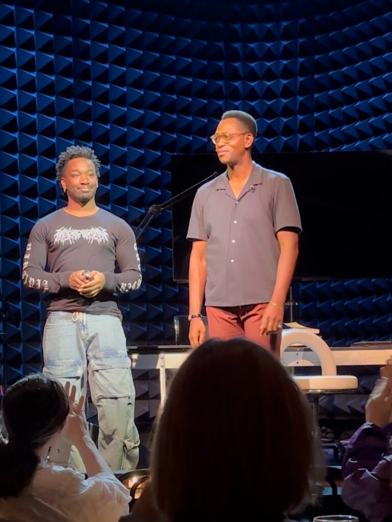 Two men stand on stage