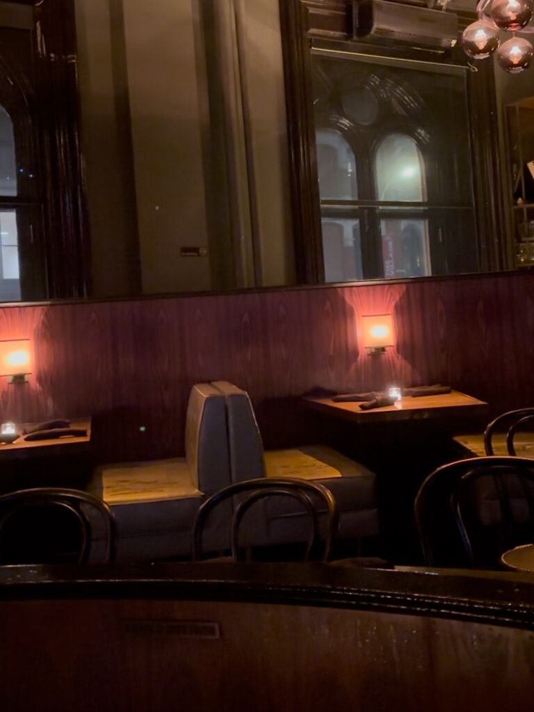 A photo of an empty booth inside of Joe's Pub with a small candle in the center of the table