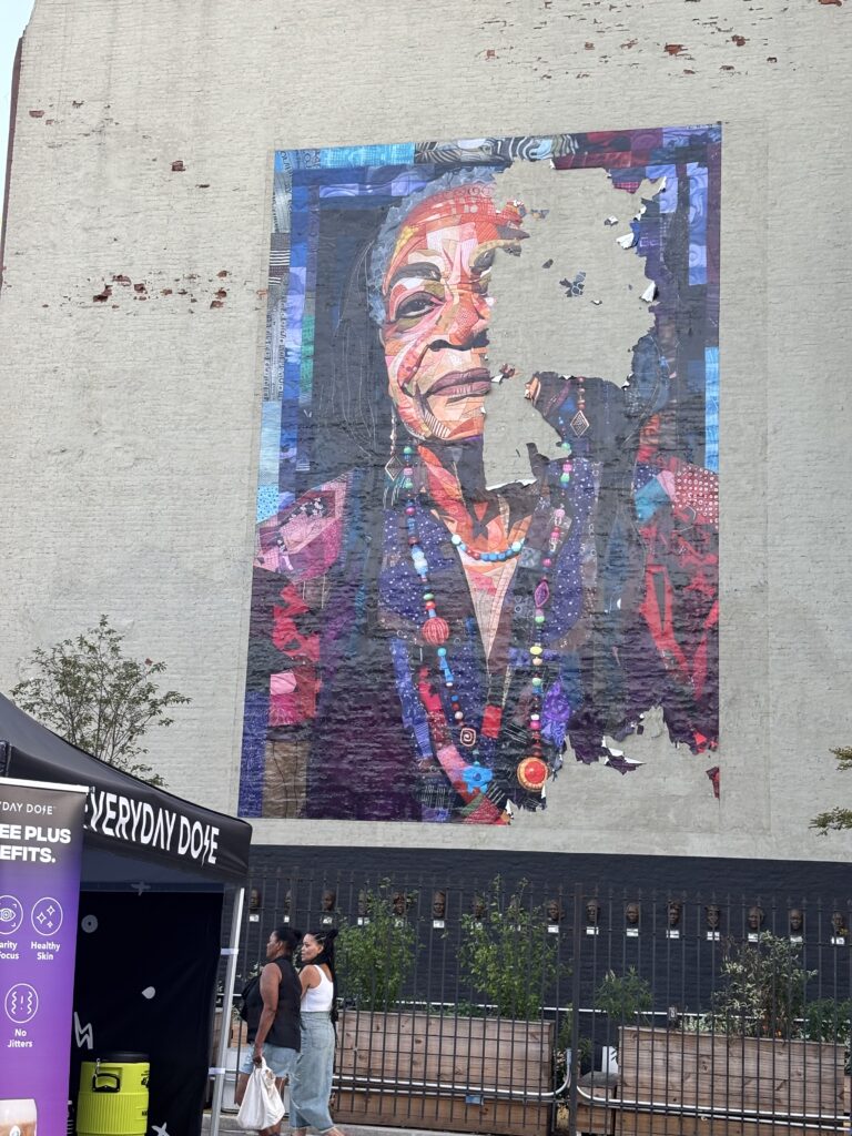 a painting of a distinguished brown-skinned woman is peeling off the side of a building