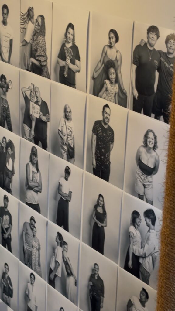 An array of black and white photos of various people is neatly organized on the wall